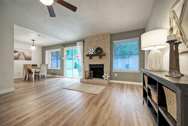 615 Twin Oak Trl, Cedar Park, TX 78613 - unfurnished living room featuring a textured ceiling, wood finished floors, lofted ceiling, ceiling fan, and a fireplace