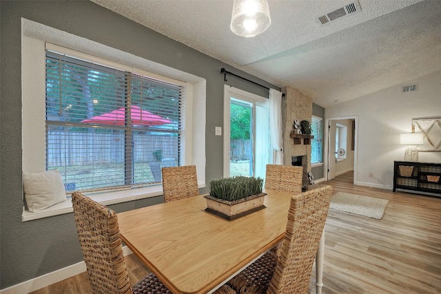 615 Twin Oak Trl, Cedar Park, TX 78613 - dining space featuring a textured ceiling, vaulted ceiling, wood finished floors, and a stone fireplace