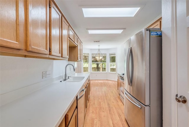 14710 Montoro Dr, Austin, TX 78728 - kitchen featuring stainless steel appliances, a sink, light wood-style flooring, light countertops, and brown cabinets