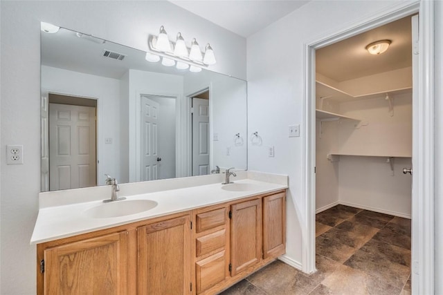 14710 Montoro Dr, Austin, TX 78728 - full bathroom with double vanity, stone finish flooring, a walk in closet, and baseboards