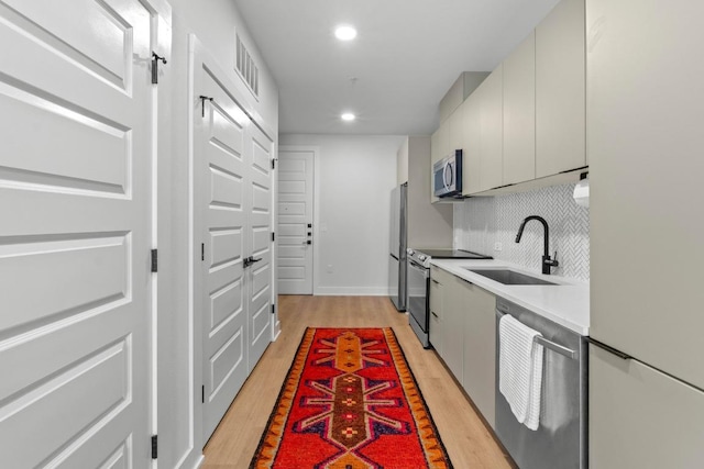 2500 Longview St Unit 112, Austin, TX 78705 - kitchen with stainless steel appliances, a sink, light wood-style floors, recessed lighting, and light countertops