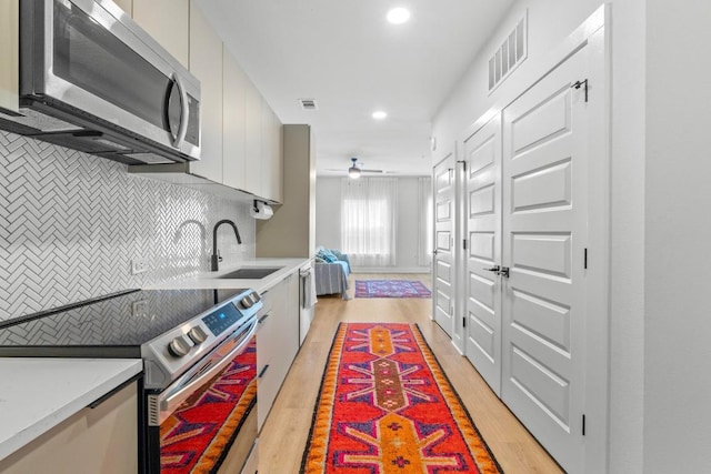 2500 Longview St Unit 112, Austin, TX 78705 - kitchen with stainless steel appliances, a sink, decorative backsplash, light wood-style floors, and light countertops