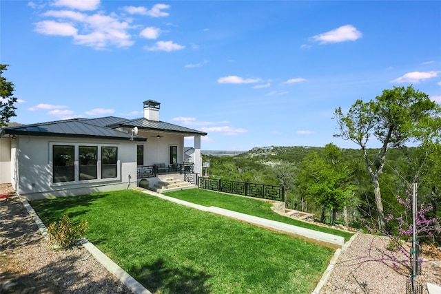 105 Golden Eagle, Horseshoe Bay, TX 78657 - back of property featuring a standing seam roof, ceiling fan, a chimney, metal roof, and stucco siding