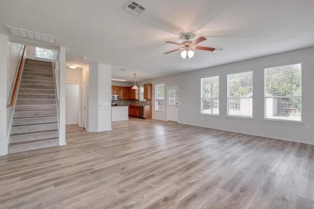 9104 China Rose Dr, Austin, TX 78724 - unfurnished living room with light wood-type flooring, a ceiling fan, and stairs