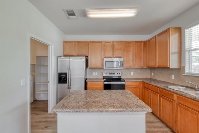 9104 China Rose Dr, Austin, TX 78724 - kitchen with appliances with stainless steel finishes, light wood-type flooring, tasteful backsplash, and a kitchen island