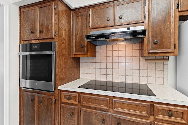 302 Council Rd, Georgetown, TX 78633 - kitchen featuring oven, under cabinet range hood, black electric stovetop, backsplash, and light countertops