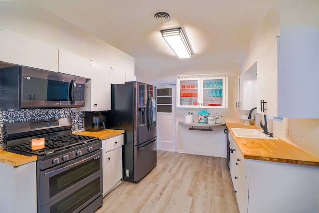 2607 Monticello Ct, San Antonio, TX 78223 - kitchen with stainless steel appliances, white cabinets, light wood-style floors, and butcher block countertops
