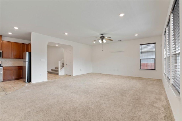 14302 Honey Gem Dr, Pflugerville, TX 78660 - unfurnished living room featuring light colored carpet, ceiling fan, recessed lighting, stairs, and arched walkways
