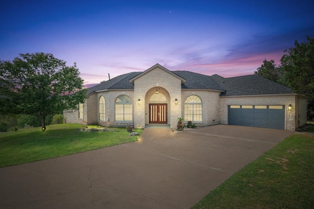 20503 Hoover Cv, Lago Vista, TX 78645 - french country inspired facade with driveway, a yard, an attached garage, a shingled roof, and brick siding