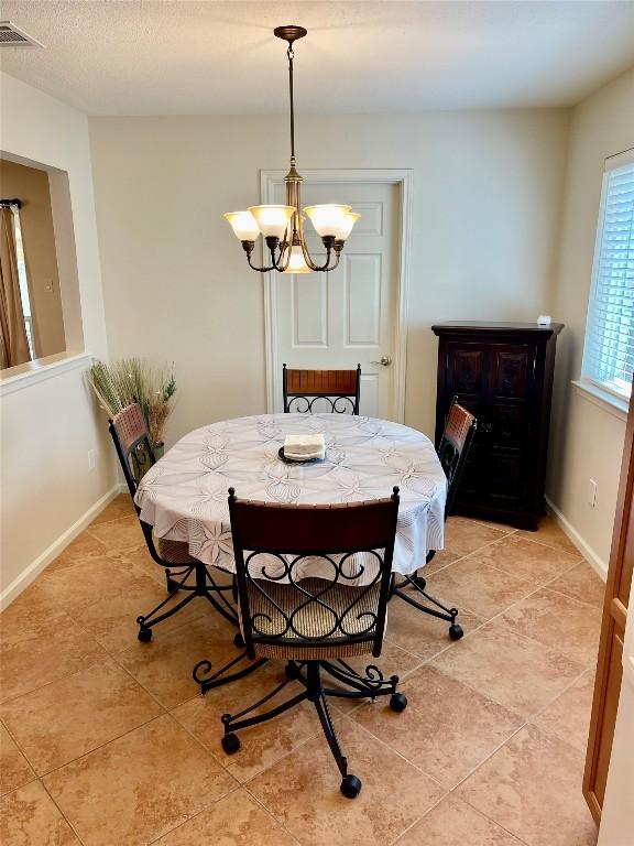 4107 Columbine Dr, Austin, TX 78727 - dining area with light tile patterned floors, a chandelier, and baseboards