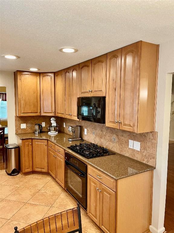 4107 Columbine Dr, Austin, TX 78727 - kitchen with black appliances, decorative backsplash, dark stone countertops, a textured ceiling, and brown cabinets