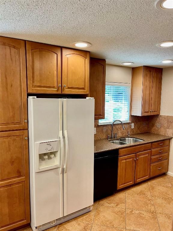 4107 Columbine Dr, Austin, TX 78727 - kitchen with white fridge with ice dispenser, black dishwasher, a sink, brown cabinets, and light tile patterned floors