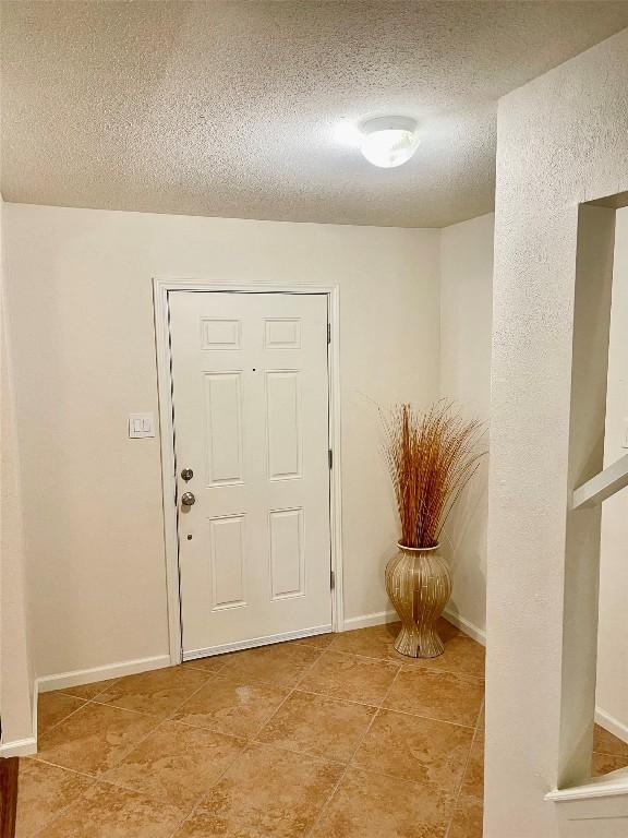 4107 Columbine Dr, Austin, TX 78727 - entryway featuring a textured ceiling, baseboards, and light tile patterned floors