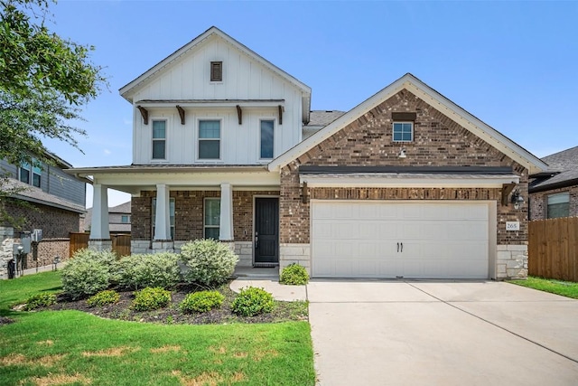 265 Fawn River Run, Kyle, TX 78640 - view of front of house featuring board and batten siding, driveway, brick siding, covered porch, and an attached garage