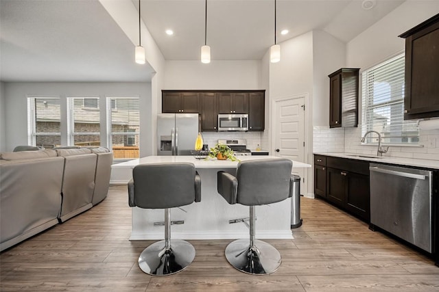 265 Fawn River Run, Kyle, TX 78640 - kitchen with appliances with stainless steel finishes, a sink, open floor plan, light countertops, and dark brown cabinetry