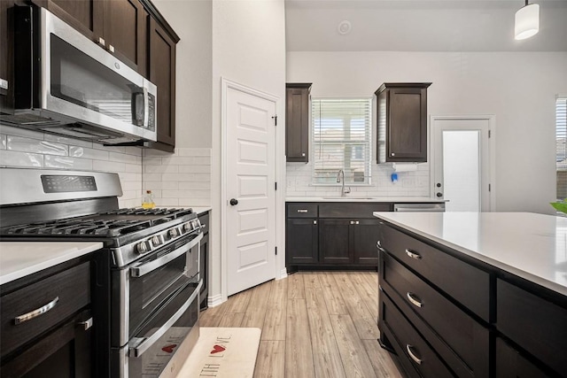 265 Fawn River Run, Kyle, TX 78640 - kitchen featuring appliances with stainless steel finishes, a sink, light wood-type flooring, light countertops, and decorative backsplash