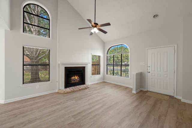 8407 Mount Shasta Cv, Round Rock, TX 78681 - unfurnished living room with high vaulted ceiling, light wood-style flooring, a lit fireplace, ceiling fan, and baseboards