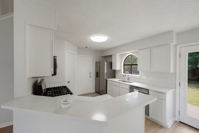 8407 Mount Shasta Cv, Round Rock, TX 78681 - kitchen featuring appliances with stainless steel finishes, a textured ceiling, white cabinets, and a peninsula
