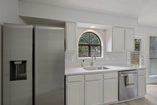 8407 Mount Shasta Cv, Round Rock, TX 78681 - kitchen with appliances with stainless steel finishes, a sink, a textured ceiling, light countertops, and white cabinets