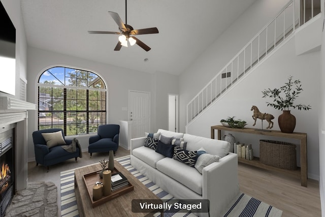 8407 Mount Shasta Cv, Round Rock, TX 78681 - living area with a lit fireplace, stairs, a ceiling fan, high vaulted ceiling, and wood finished floors