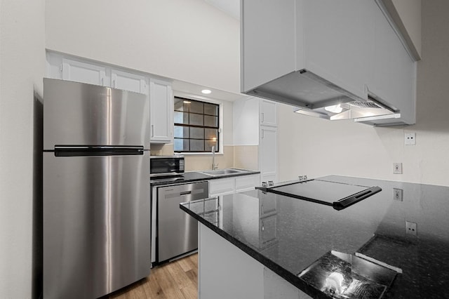 1908 San Antonio St Unit 313, Austin, TX 78705 - kitchen with stainless steel appliances, a sink, white cabinetry, light wood-style floors, and dark stone counters