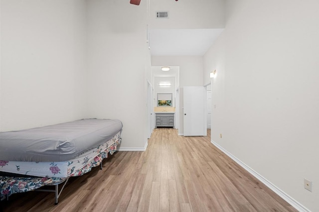 1908 San Antonio St Unit 313, Austin, TX 78705 - bedroom featuring light wood-style flooring, a high ceiling, baseboards, ensuite bath, and a ceiling fan