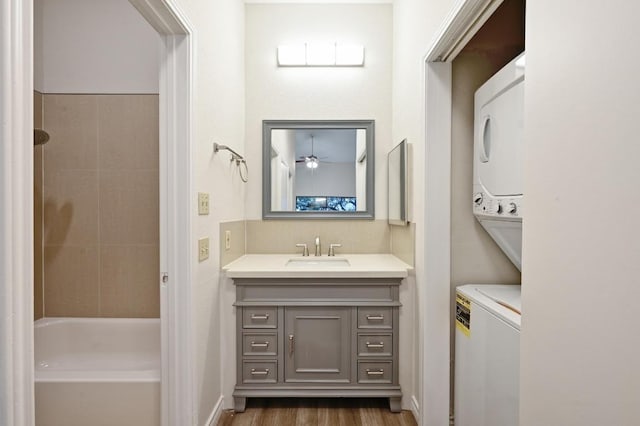 1908 San Antonio St Unit 313, Austin, TX 78705 - full bath with stacked washer / drying machine, vanity, wood finished floors, bathing tub / shower combination, and a ceiling fan