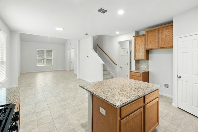 13208 Olivers Way, Manchaca, TX 78652 - kitchen featuring a center island, brown cabinets, stainless steel gas range, light stone countertops, and open floor plan