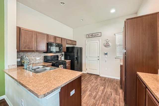 814 Hatton Hill Ct, Austin, TX 78725 - kitchen featuring black appliances, a sink, backsplash, wood finished floors, and light countertops