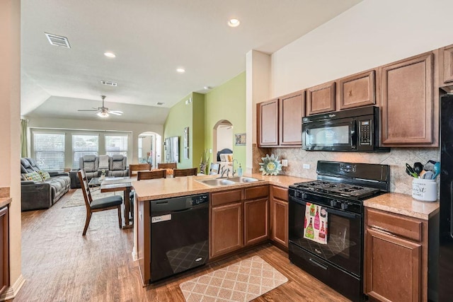 814 Hatton Hill Ct, Austin, TX 78725 - kitchen with black appliances, vaulted ceiling, a peninsula, light wood finished floors, and light countertops