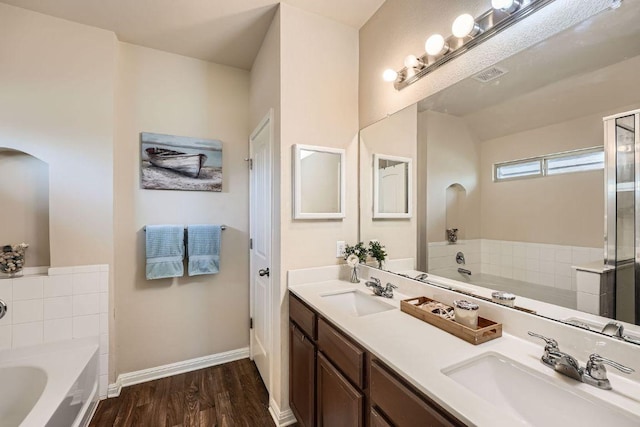 814 Hatton Hill Ct, Austin, TX 78725 - bathroom featuring a garden tub, double vanity, baseboards, and wood finished floors