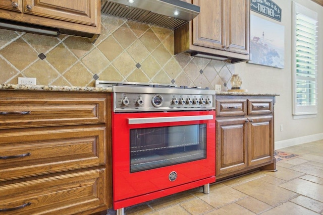 2513 Rusty Spur, Leander, TX 78641 - kitchen featuring stainless steel stove, custom range hood, baseboards, backsplash, and stone tile flooring