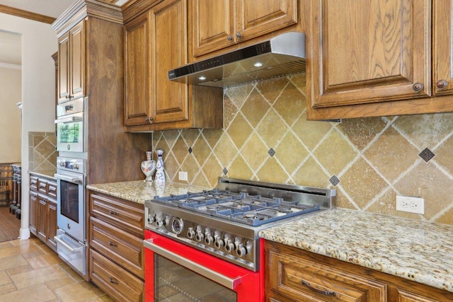 2513 Rusty Spur, Leander, TX 78641 - kitchen with under cabinet range hood, appliances with stainless steel finishes, brown cabinets, a warming drawer, and tasteful backsplash