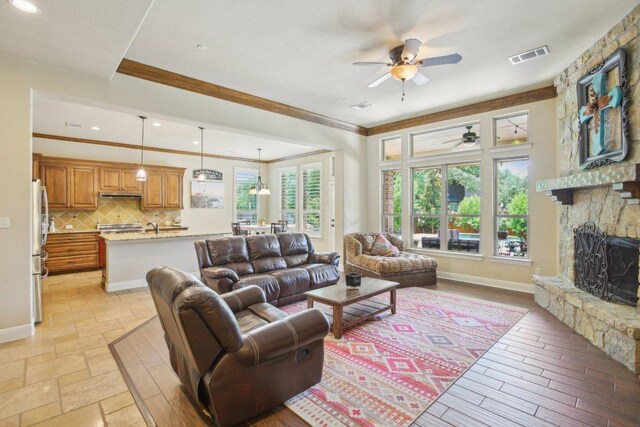 2513 Rusty Spur, Leander, TX 78641 - living area featuring a ceiling fan, crown molding, a stone fireplace, baseboards, and recessed lighting