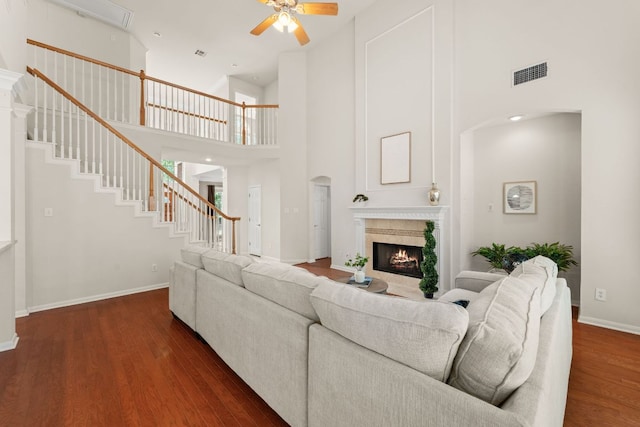 10617 Bramblecrest Dr, Austin, TX 78726 - living room featuring a ceiling fan, a high ceiling, a warm lit fireplace, wood finished floors, and baseboards