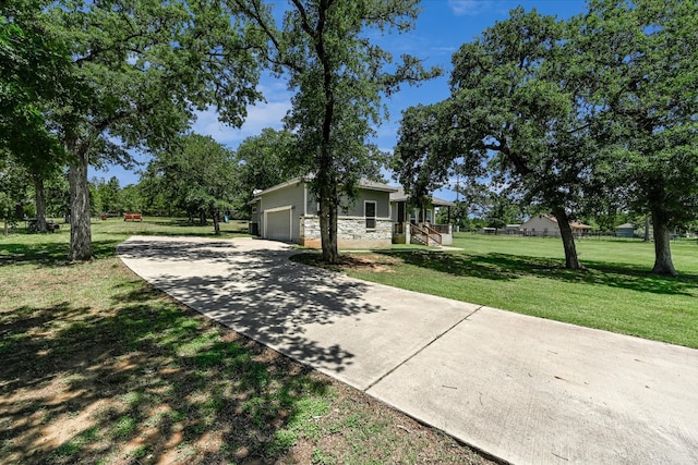 141 N Buckhorn Dr, Bastrop, TX 78602 - view of side of home with a yard, a garage, driveway, stone siding, and covered porch