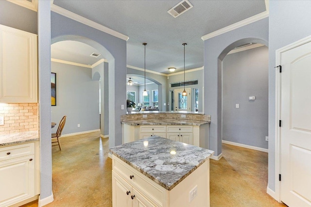 141 N Buckhorn Dr, Bastrop, TX 78602 - kitchen featuring arched walkways, cream cabinetry, baseboards, and ornamental molding