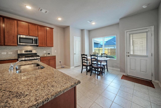 211 S Timber Brook Dr, Hutto, TX 78634 - kitchen featuring stainless steel appliances, light stone counters, brown cabinets, and recessed lighting