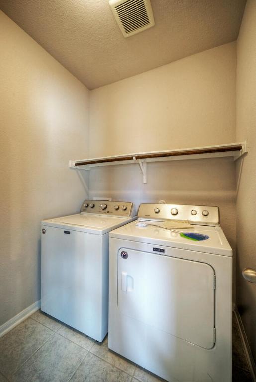 211 S Timber Brook Dr, Hutto, TX 78634 - washroom with separate washer and dryer, baseboards, light tile patterned floors, and a textured ceiling