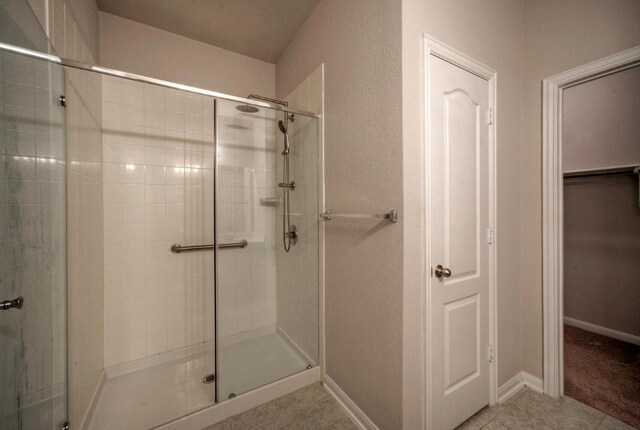 211 S Timber Brook Dr, Hutto, TX 78634 - bathroom featuring a shower stall, tile patterned flooring, and a spacious closet