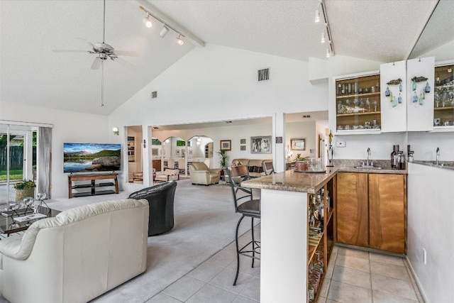 8600 Crest Ridge Cir, Austin, TX 78750 - kitchen featuring rail lighting, open floor plan, a textured ceiling, a ceiling fan, and a kitchen bar
