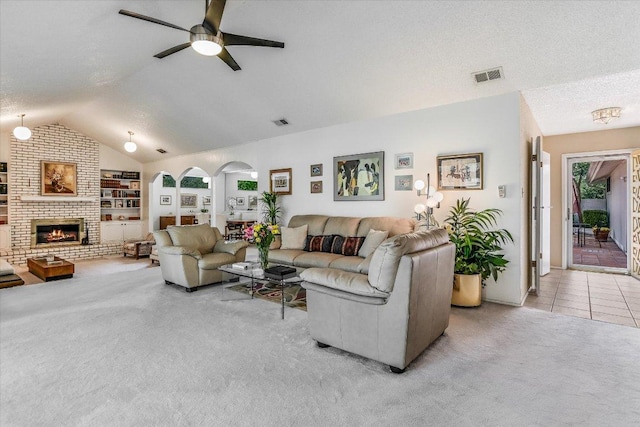 8600 Crest Ridge Cir, Austin, TX 78750 - living area featuring vaulted ceiling, a ceiling fan, carpet flooring, arched walkways, and a brick fireplace