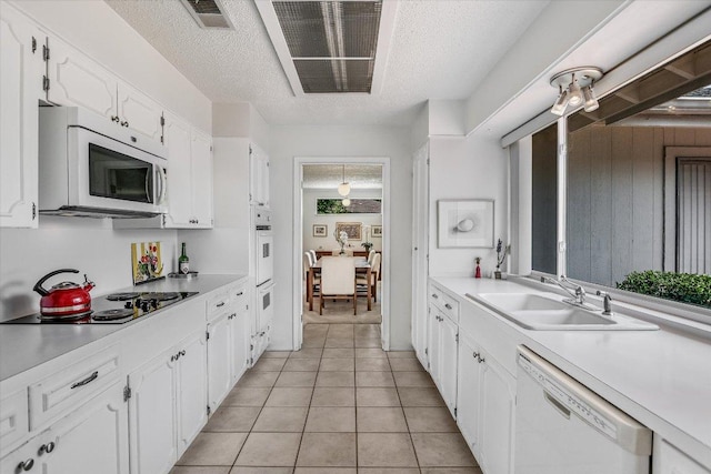 8600 Crest Ridge Cir, Austin, TX 78750 - kitchen with white appliances, white cabinets, a textured ceiling, light countertops, and light tile patterned floors