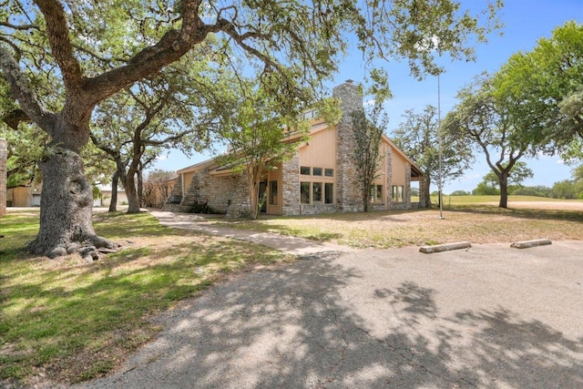 8600 Crest Ridge Cir, Austin, TX 78750 - view of side of home with a lawn, stone siding, and a chimney