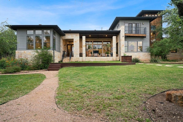 332 Rugged Earth Dr, Austin, TX 78737 - back of house featuring stone siding, a lawn, and a balcony