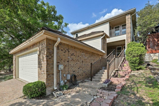 6029 Mount Bonnell Cv, Austin, TX 78731 - view of side of home featuring a balcony, a garage, concrete driveway, stairway, and brick siding