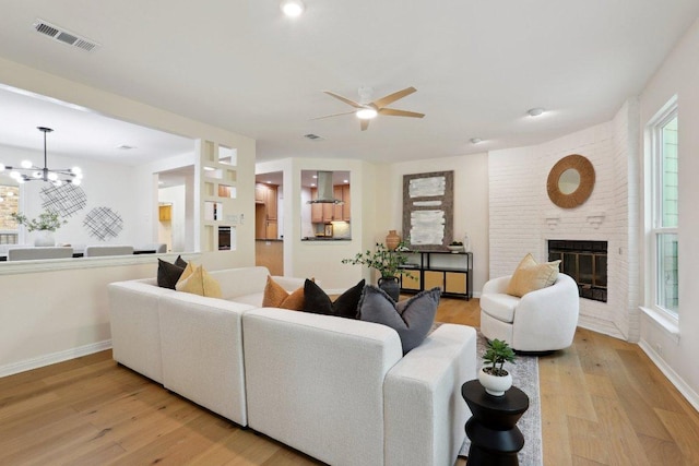 6029 Mount Bonnell Cv, Austin, TX 78731 - living area with ceiling fan, light wood-type flooring, a chandelier, a fireplace, and plenty of natural light