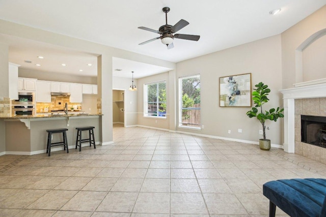 1252 Fall Creek Loop, Cedar Park, TX 78613 - living room with light tile patterned floors, a fireplace, a ceiling fan, baseboards, and recessed lighting