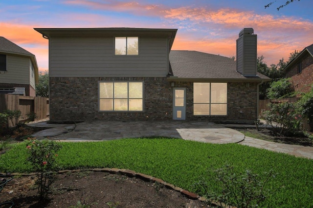 1252 Fall Creek Loop, Cedar Park, TX 78613 - back of property at dusk featuring a patio area, brick siding, and a chimney