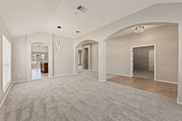1129 Wigwam Dr, Leander, TX 78641 - unfurnished living room featuring lofted ceiling, carpet floors, tile patterned flooring, and arched walkways